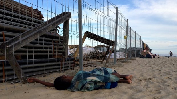 A boy sleeps next to ongoing construction of the Olympic Beach Volleyball Arena on Copacabana Beach on on Monday.