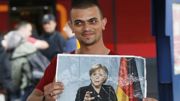 A refugee carries a picture of German Chancellor Angela Merkel as he arrives in Munich in 2015. 
