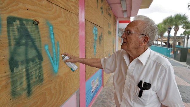 Zeno Louizes spray paints markings on his three stores along the Boardwalk and Pier in Daytona Beach, Florida.