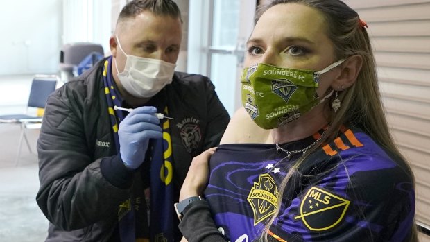 A Seattle Sounders soccer team fan gets a COVID-19 vaccine injection at the Lumen Field sports stadium's concourse, prior to the game.