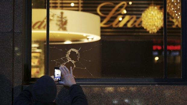 A man takes a photo of the broken glass from vandalised windows at the Lindt cafe in Martin Place, Sydney.