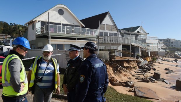 Warringah Council group manager of natural environments Todd Dickinson (left) and consultant Angus Gordon (second from left) speak with police during an inspection of damaged beachfront homes.