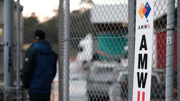 A sacked maintenance workers stands outside the brewery gates.