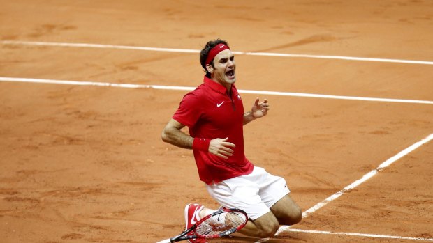 Overcome: Roger Federer collapses on the French clay after helping Switzerland claim their first Davis Cup title.