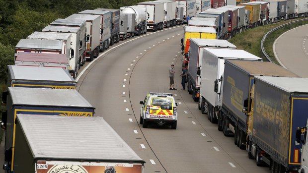 A police vehicle drives past lorries are backed up on the M20 motorway which leads from London to the Channel Tunnel terminal at Ashford.