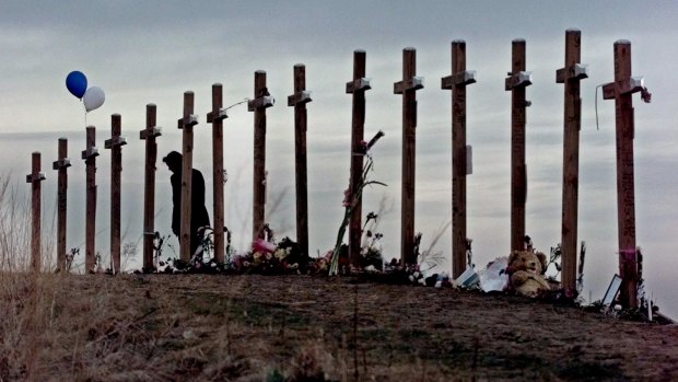 A woman stands among 15 crosses on a hill above Columbine High School in remembrance of the 15 people who died during a school shooting on April 20, 1999. 
