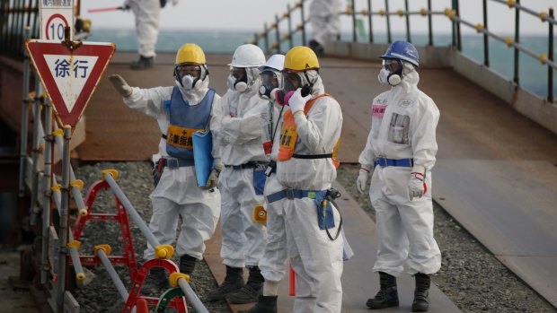 Workers stand near the No. 3 and No. 4 reactor buildings at the Fukushima No. 1 nuclear power plant on Wednesday.
