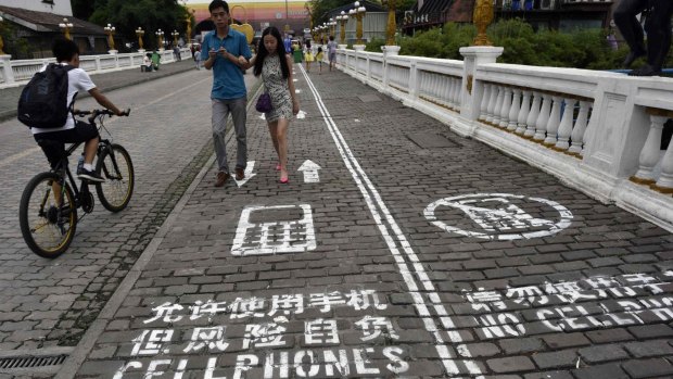 Pedestrians walk down a footpath in Chongqing in China divided into two sides - one marked with "Cellphones walk in this lane at your own risk" and the other "No cellphones", as an attempt to reduce pedestrian incidents, local media reported. 