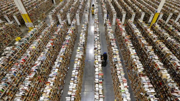 Going from big to small. An Amazon.com employee stocks products along one of the many miles of aisles at an Amazon.com Fulfillment Centre.