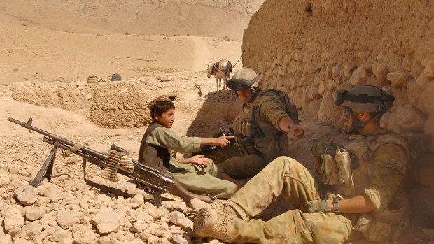 An Afghan boy sits with Reconstruction Task Force soldiers during a meeting with local leaders in Oruzgan Province, Afghanistan. 