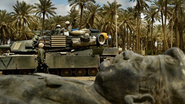 A US tank unit passes one of the many fallen statues of former Iraq dictator Saddam Hussein in Baghdad in 2003.