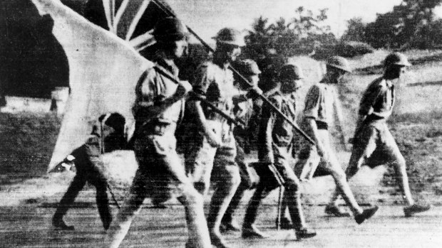 A surrender party from the British forces is escorted by a Japanese soldier in Singapore. They carry the white flag as well as the Union Jack. Lieutenant-General A. E. Percival (1887-1966) is the figure on the extreme right.