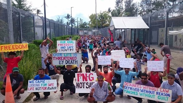 In this undated photo released by Refugee Action Coalition, refugees and asylum seekers hold up banners during a protest at the Manus Island immigration detention centre.