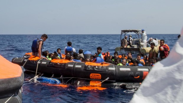 Surviving migrants are brought aboard Irish and Italian Navy life-boats in the area where their wooden boat capsized and sank off the coast of Libya on Wednesday.