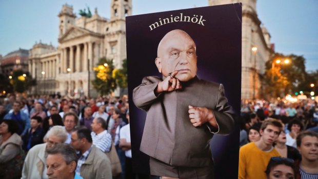 A man holds a banner depicting Hungarian Premier Viktor Orban, the reads "mini-prime minister" during a protest against Orban's policies in Budapest.