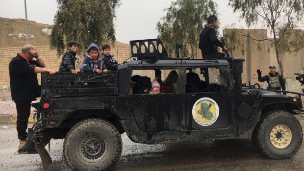 Iraqi special forces transport civilians fleeing their homes during clashes between Iraqi security forces and Islamic State group on the western side of Mosul, Iraq. 
