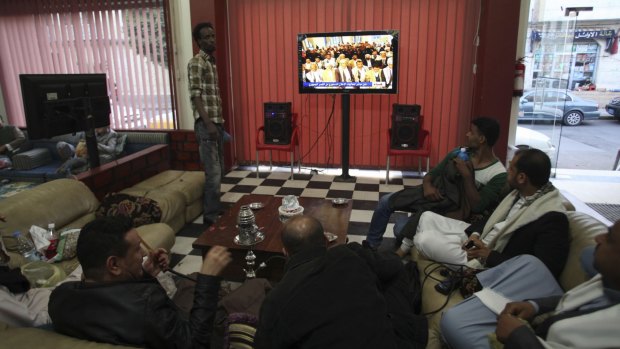 Yemenis watch the Houthis' televised announcement that they will dissolve parliament.