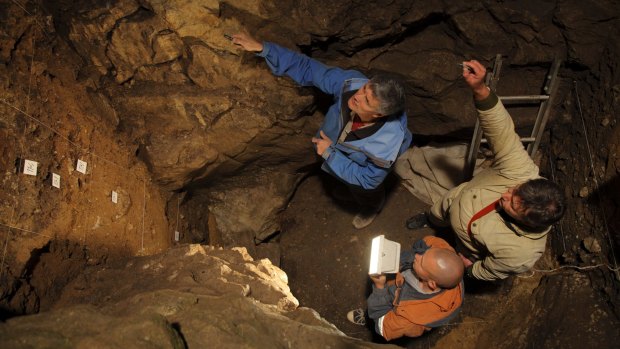 Clockwise from top: Richard Roberts, Vladimir Ulianov and Maxim Kozlikin plan the sampling of sediments in the East Chamber of Denisova Cave in Russia. 