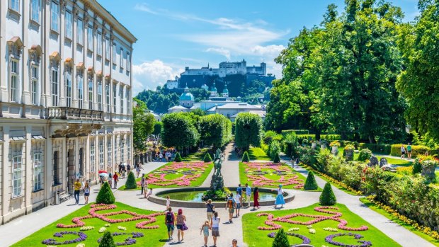 Visitors stroll around Mirabell Garden, the old historic Fortress Hohensalzburg in the background, in Salzburg, Austria.