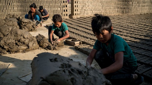 Phursang Tamang, 10, (centre) works with his brother and parents at a brick factory in Bhaktapur. The Tamang family's house was damaged beyond repair.