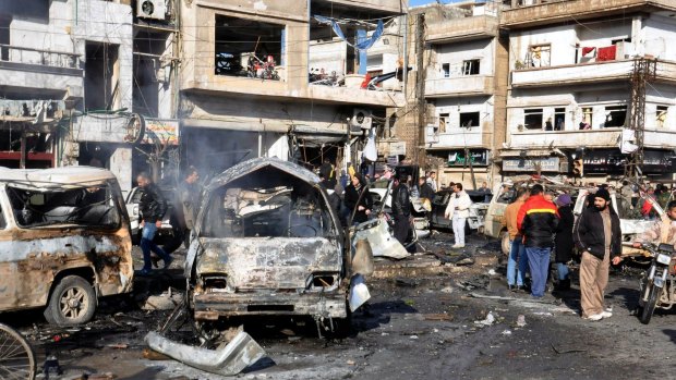 Syrian citizens gather at the scene where twin bombs exploded at a government-run security checkpoint in the Homs neighbourhood of Zahraa, Syria.