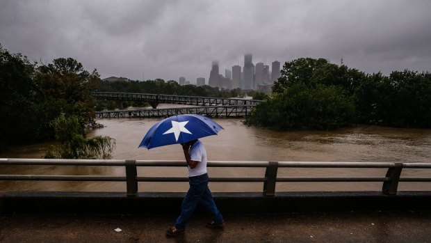 Armando Bustsamante walks along the street over Buffalo Bayou as flood waters from Tropical Storm Harvey flow towards central Houston.