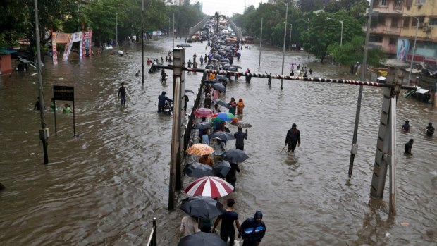 People walk through a waterlogged street following heavy rains in Mumbai, India, on Tuesday.