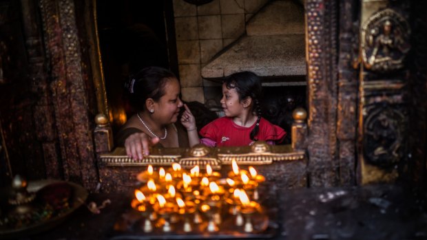 A young girl caresses her mother's nose in a temple in Kathmandu, Nepal, on Monday. 