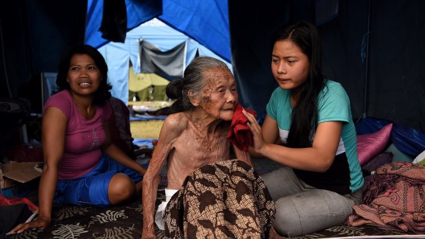 Ketut Setiari, right, bathes her 115-year-old great grandmother Nengah Brata in a tent at an evacuation camp in Klungkung, Bali.