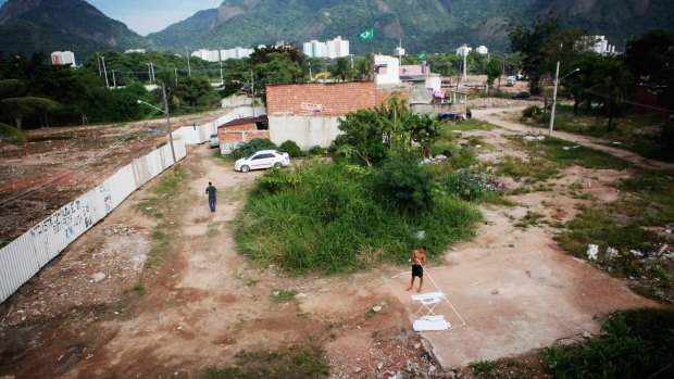Destroyed: Residents stand in the mostly demolished Vila Autodromo favela community, a former fishing colony in Rio de Janeiro.