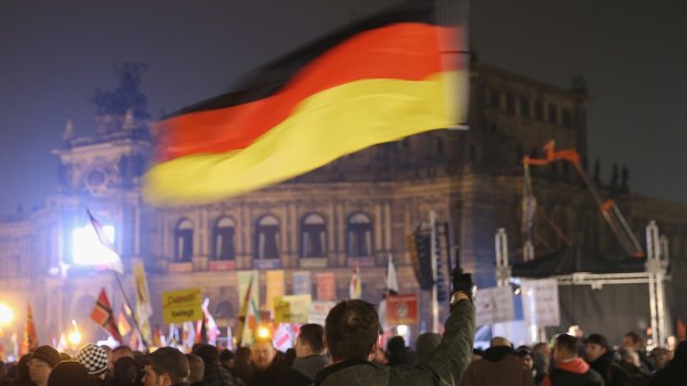 Supporters of the Pegida movement, including a man waving a German flag, gather on October 19, on the first anniversary of the first Pegida march.