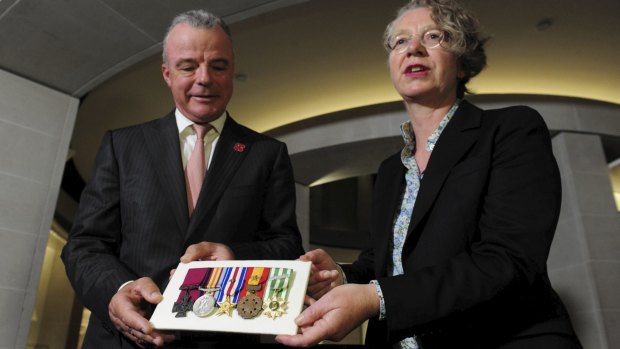 Australian War Memorial director Brendan Nelson receives the Victoria Cross and cluster of medals belonging to the late Peter Badcoe from Mandy Paul.