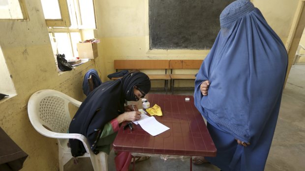An Afghan woman, right, waits to receive a ballot paper at a polling station in Jalalabad  in June 2014.