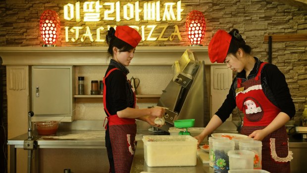 Smartly uniformed women team up to make a pie at an upscale pizza restaurant on Mirae Scientists Street in Pyongyang, North Korea.