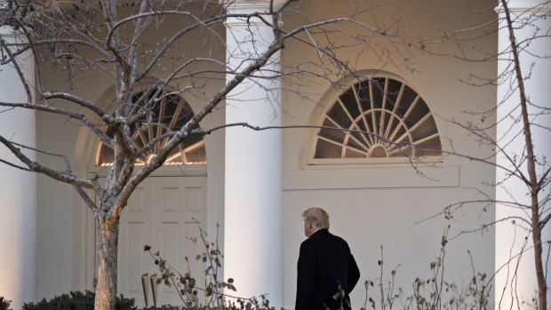 US President Donald Trump walks through the Colonnade of the White House a day before the threatened shutdown and two days before his first inauguration anniversary.
