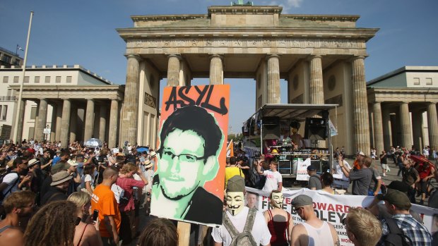 A protester carries a picture of Snowden with the German word for 'asylum' during a 2013 protest in Berlin. 