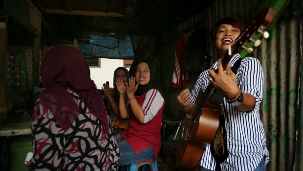 Titi Juwariyah, right, performs in a small streetside restaurant in Jakarta. 