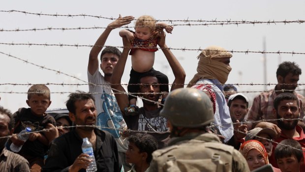 Syrian refugees on the Syrian side of the border crossing at Akcakale on Monday.