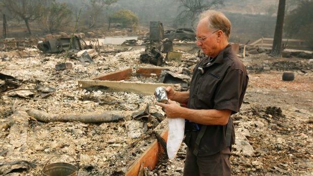 Chuck Rippey looks over a cup found in his parents' destroyed home in Napa.