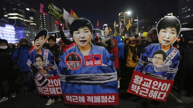 Protesters hold cutouts of President Park Geun-hye as they march during a candle light vigil calling for her to step down on January 14.