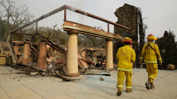 Napa County firemen walk through the remains of the Signorello Estate winery.