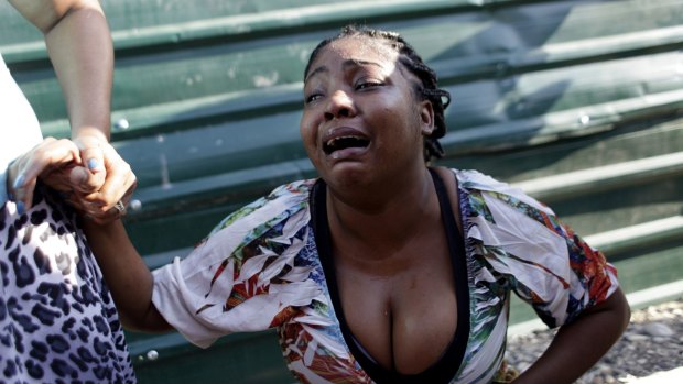 A woman cries after a family member was killed when a carnival float hit power lines in Port-au-Prince. At least 18 people were killed and 60 injured in the accident.