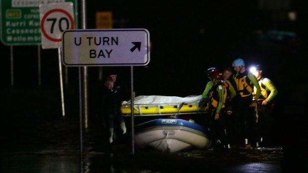 Police divers retrieve the body of an 86-year-old woman whose car was swept away.