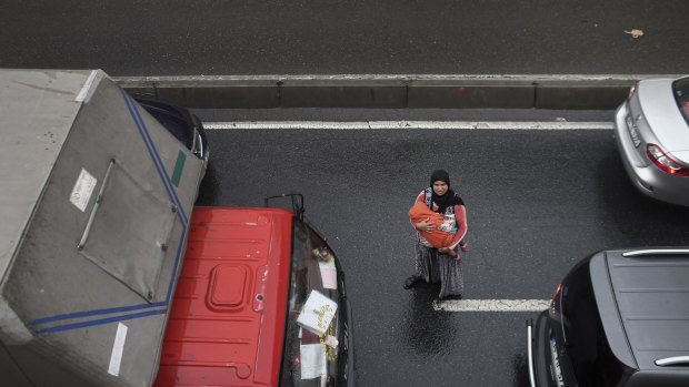 A Syrian woman begs for money from passing motorists in Istanbul.