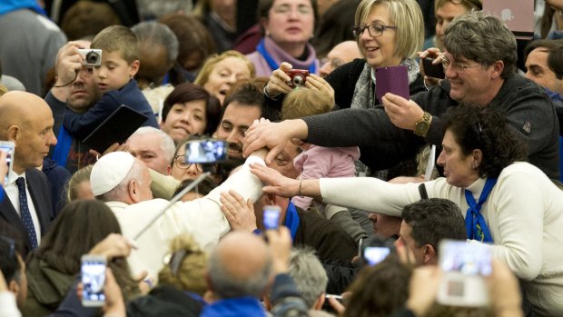 Pope Francis is mobbed by the faithful as he arrives at the Vatican on Saturday.