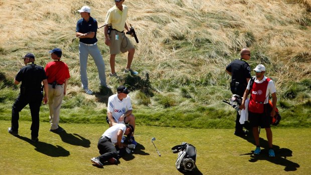 Jason Day of Australia is overcome by dizziness on the fairway of the ninth hole.