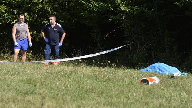 Rescuers stand next to the covered body of a skydiver who was killed in the crash. 