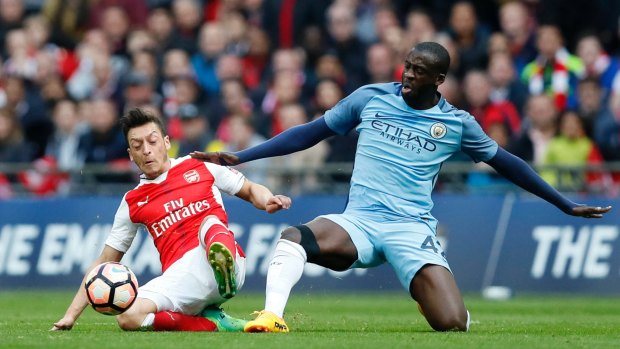 Arsenal's Mesut Ozil (left) vies for the ball with Manchester City's Yaya Toure.