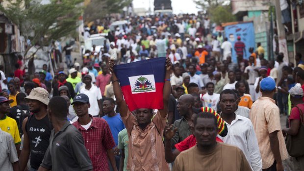 Anti-government protesters hold up the Haitian flag. Annual Carnival celebrations have been sidelined by the political demonstrations.