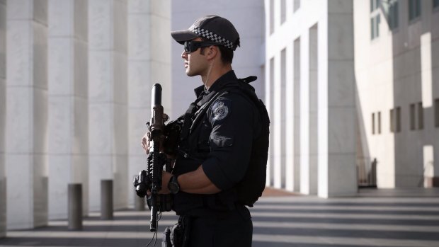 An armed AFP officer stands guard outside Parliament House in Canberra.
